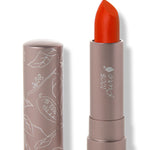 100% Pure Cactus Bloom matte lipstick with a slanted vivid orange red tip extended from a taupe tube; its matching cap stands beside it with white botanical line drawings.