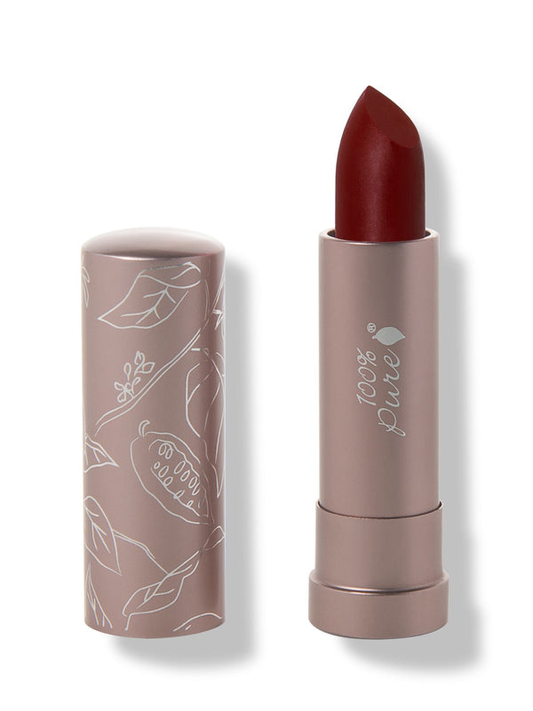 100% Pure Desert Rose matte lipstick with a slanted dark burgundy red tip extended from a taupe tube; its matching cap stands beside it with white botanical line drawings.