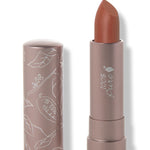 100% Pure Mojave matte lipstick with a slanted warm orange brown tip extended from a taupe tube; its matching cap stands beside it with white botanical line drawings.