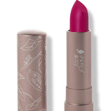 100% Pure Marrakesh matte lipstick with a slanted vivid fuchsia pink tip extended from a taupe tube; its matching cap stands beside it with white botanical line drawings.