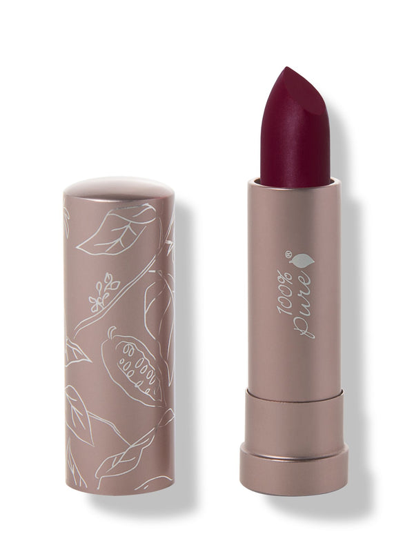 100% Pure Oasis matte lipstick with a slanted dark plum red tip extended from a taupe tube; its matching cap stands beside it with white botanical line drawings.