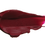 A thick smear of dark plum red Oasis matte lipstick on white, with a smooth centre and raised, creamy ridges around the edges.