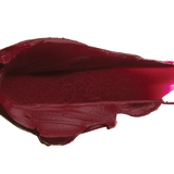 A thick smear of dark plum red Oasis matte lipstick on white, with a smooth centre and raised, creamy ridges around the edges.