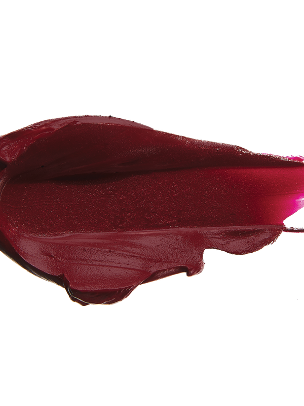 A thick smear of dark plum red Oasis matte lipstick on white, with a smooth centre and raised, creamy ridges around the edges.