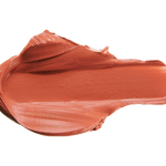 A warm peach-rose lipstick swatch is spread into a thick horizontal smear. Raised folds gather along its upper edge, while the centre is broad and smooth, with fine streaks along the lower edge.