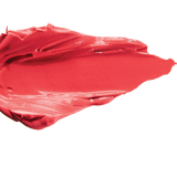 A thick smear of bright coral pink Prickly Pear matte lipstick on white, with a smooth centre and raised, creamy ridges around the edges.