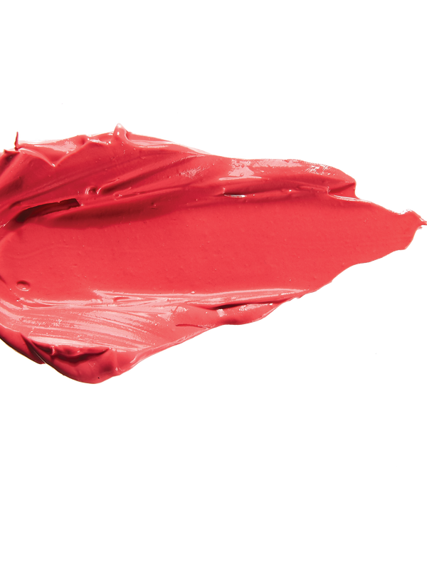 A thick smear of bright coral pink Prickly Pear matte lipstick on white, with a smooth centre and raised, creamy ridges around the edges.