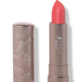100% Pure Strawberry Cactus matte lipstick with a slanted bright coral red tip extended from a taupe tube; its matching cap stands beside it with white botanical line drawings.