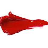 Red Velvet 100% Pure Lip Caramel swatch: thick, glossy rich red liquid lipstick spread into an elongated smear, with raised ridges and a tapering streak at one end.