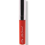 Scotch Kiss 100% Pure Lip Caramel: vivid orange-red liquid lipstick in a closed clear tube with white script lettering and a reflective silver cap.