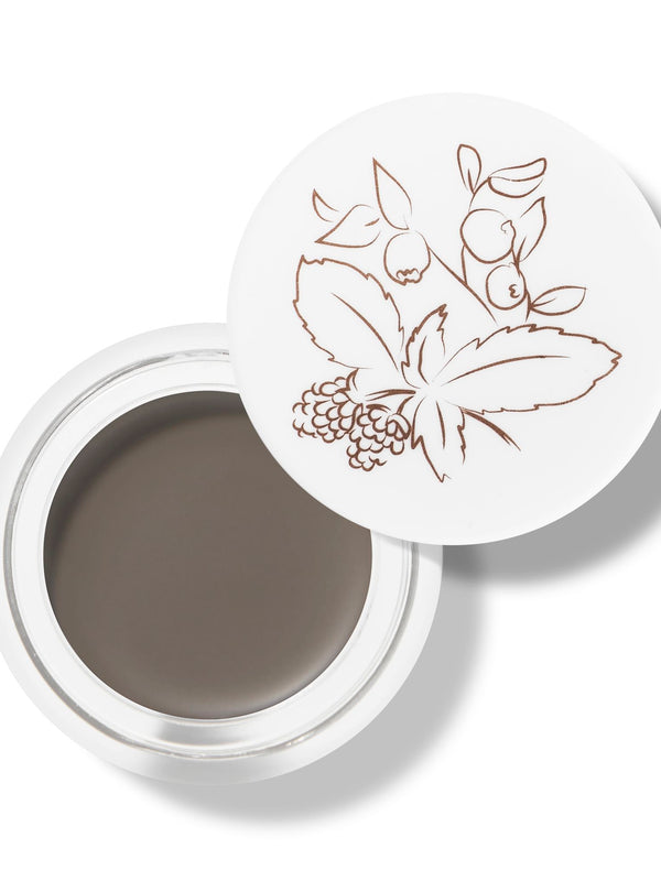 100% Pure Long Last Brows in Taupe: an open white pot filled with grey-brown brow cream. A fine drawing of leaves and berries decorates the white lid resting behind the pot.