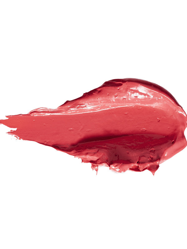 A thick smear of Magnolia lipstick in bright coral pink, with a smooth glossy centre, raised creamy ridges and a tapered end on white.