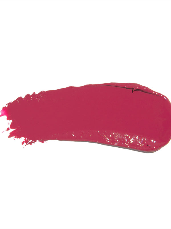A broad swatch of Narcissus lipstick in deep fuchsia pink, with a smooth glossy surface and fine streaks at one end on white.