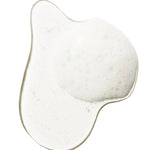 A clear swatch of Burdock and Neem shampoo forms an irregular pool on white. Fine white foam and small bubbles collect across its centre and along one side.