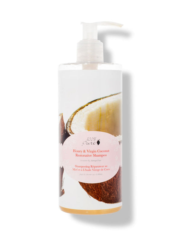 A white pump bottle labelled 100% Pure Honey & Virgin Coconut Restorative Shampoo has a large photograph of an opened coconut behind a pale pink oval label. Golden liquid is visible at the bottom.