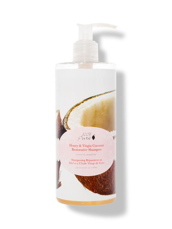 A white pump bottle labelled 100% Pure Honey & Virgin Coconut Restorative Shampoo has a large photograph of an opened coconut behind a pale pink oval label. Golden liquid is visible at the bottom.