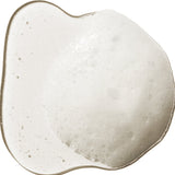 A translucent swatch of 100% Pure Kelp & Mint Volumising Shampoo, forming an uneven puddle with white froth and small bubbles through the centre.