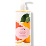 100% Pure Yuzu & Pomelo Glossing Shampoo in a white pump bottle, with a large pink citrus slice, yellow fruit, green leaves and a round pink label on the front.