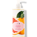 100% Pure Yuzu & Pomelo Glossing Shampoo in a white pump bottle, with a large pink citrus slice, yellow fruit, green leaves and a round pink label on the front.