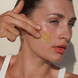 Woman applying a dab of Mukti Deep Cleanse Enzyme Mask to her cheek