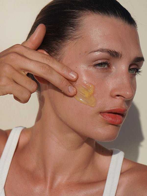 Woman applying a dab of Mukti Deep Cleanse Enzyme Mask to her cheek