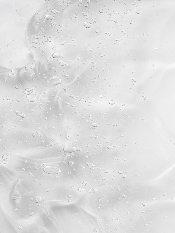 Creamy gel texture of KORA Organics Renewing Hand and Body Wash swatched against a peach background