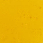 Close-up of golden-yellow Noni Radiant Eye Oil with small bubbles scattered through its smooth, translucent surface.
