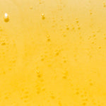 Close-up of golden-yellow Kakadu Plum Vitamin C Serum dotted with tiny bubbles and a few larger round air bubbles.