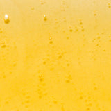 Close-up of golden-yellow Kakadu Plum Vitamin C Serum dotted with tiny bubbles and a few larger round air bubbles.