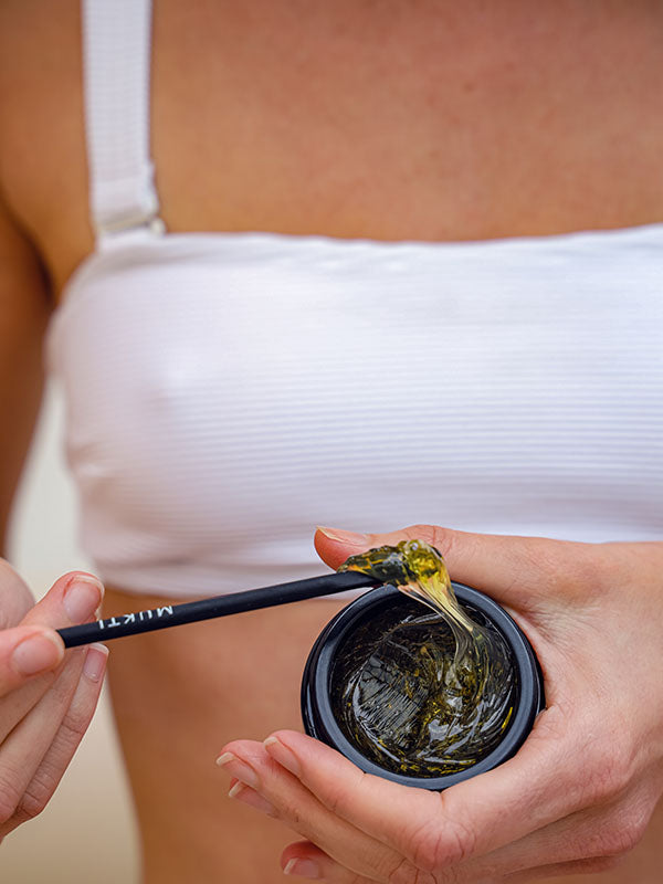 Open jar of Mukti Deep Cleanse Enzyme Mask with its honey-like gel and Mukti spatula