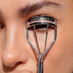 Woman curling her lashes with the Ere Perez Spectacular Eyelash Curler