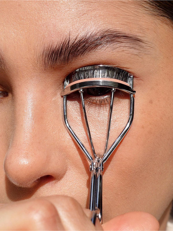 Woman curling her lashes with the Ere Perez Spectacular Eyelash Curler