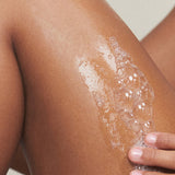 Model lathering KORA Organics Renewing Hand and Body Wash onto her skin