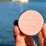 SunButter Protea Tint Protective Lip Zinc held by the water