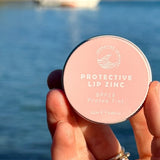 SunButter Protea Tint Protective Lip Zinc held by the water