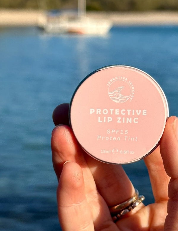 SunButter Protea Tint Protective Lip Zinc held by the water