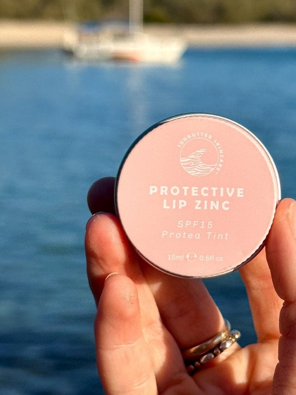 SunButter Protea Tint Protective Lip Zinc held by the water