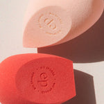 Ere Perez Bio All-Beauty Sponges in peach and coral lying in sunlight