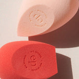 Ere Perez Bio All-Beauty Sponges in peach and coral lying in sunlight