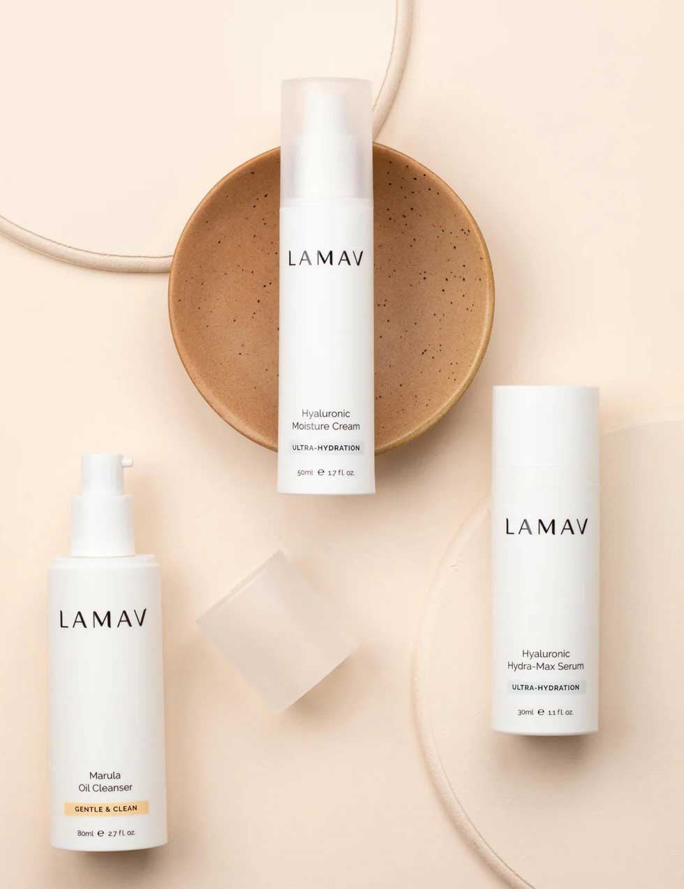 Three LAMAV Hydration Skin Discovery Pack products are displayed on a beige surface with a tan ceramic dish, featuring three essentials for ultimate hydration from LAMAV.