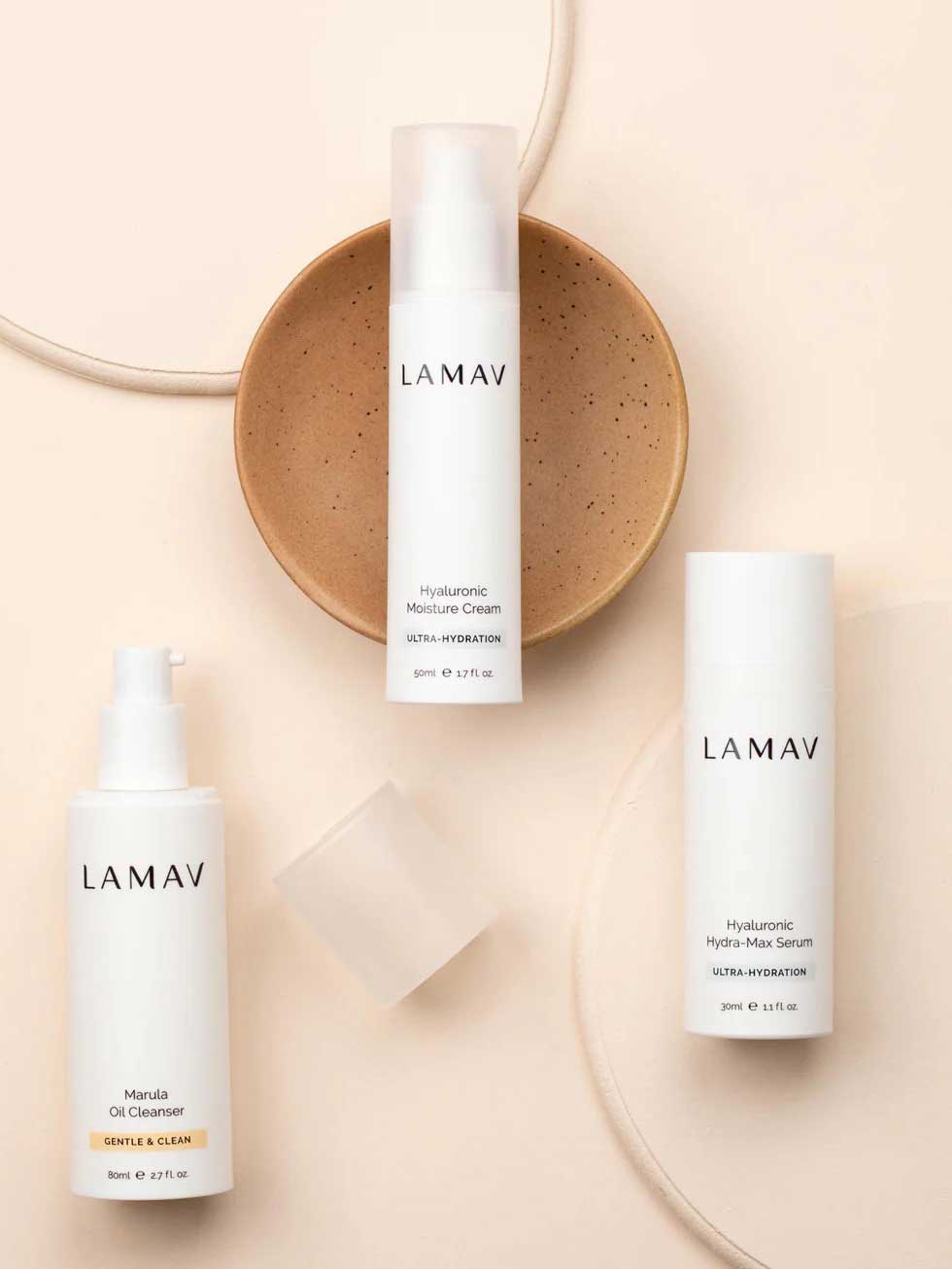 Three LAMAV Hydration Skin Discovery Pack products are displayed on a beige surface with a tan ceramic dish, featuring three essentials for ultimate hydration from LAMAV.