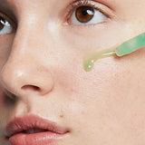 Close-up of Ere Perez Quandong Green Booster Serum dropped onto a woman's cheek from the dropper