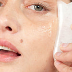 Woman pressing a soft cloth to her cheek while cleansing with Ere Perez Fig All-Beauty Jelly