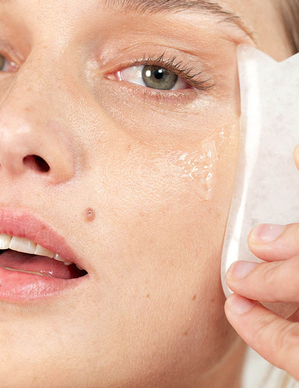 Woman pressing a soft cloth to her cheek while cleansing with Ere Perez Fig All-Beauty Jelly