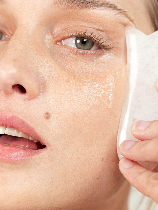Woman pressing a soft cloth to her cheek while cleansing with Ere Perez Fig All-Beauty Jelly