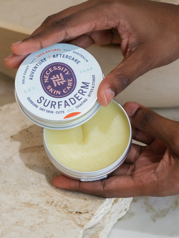 Open Necessity Surfaderm tin held in hands