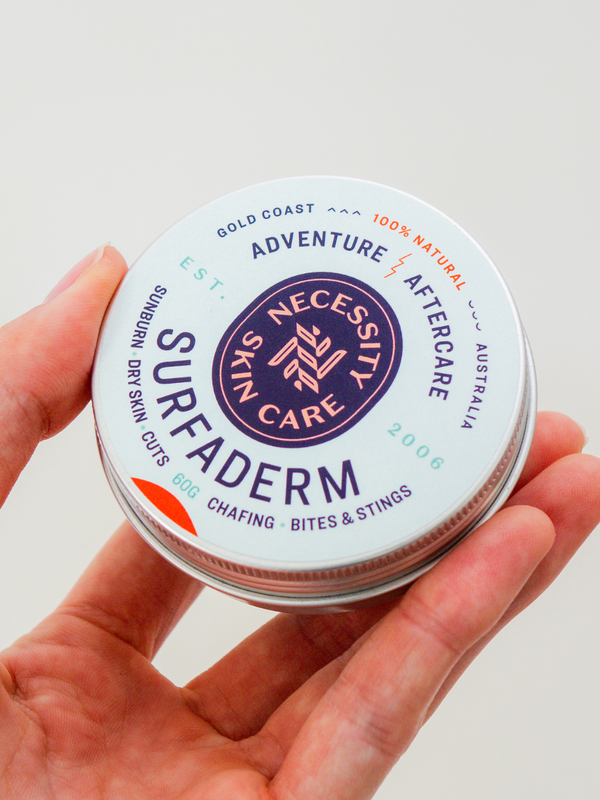 Necessity Surfaderm tin held in hand