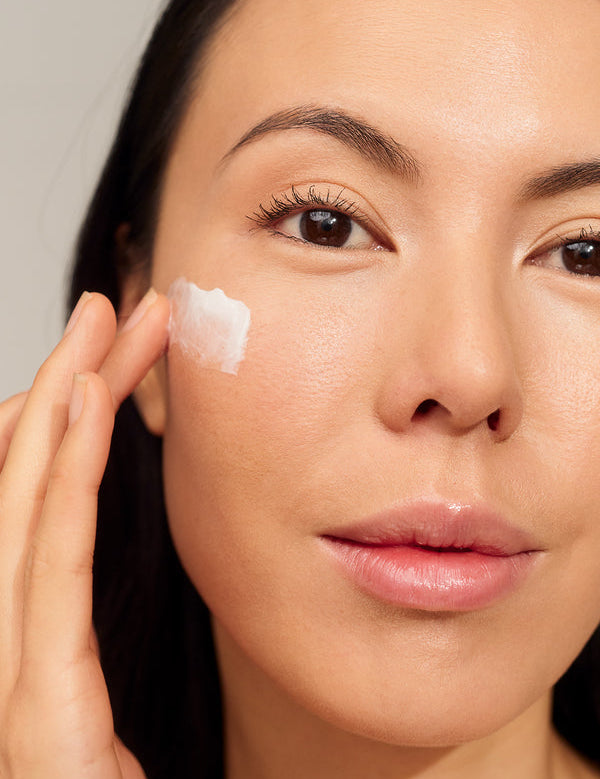 Model applying INIKA Organic Phytofuse Renew Day Cream to her face