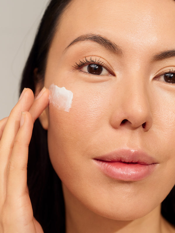 Model applying INIKA Organic Phytofuse Renew Day Cream to her face