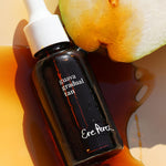 Ere Perez Guava Gradual Tan amber dropper bottle lying beside fresh guava in a pool of tan serum